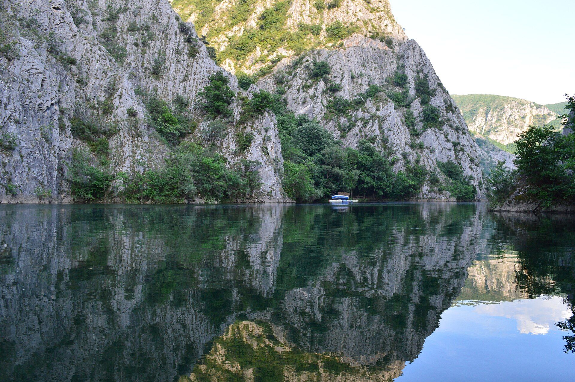 Limestone cliffs of Matka Canyon reflected in the still water of Lake Matka, North Macedonia